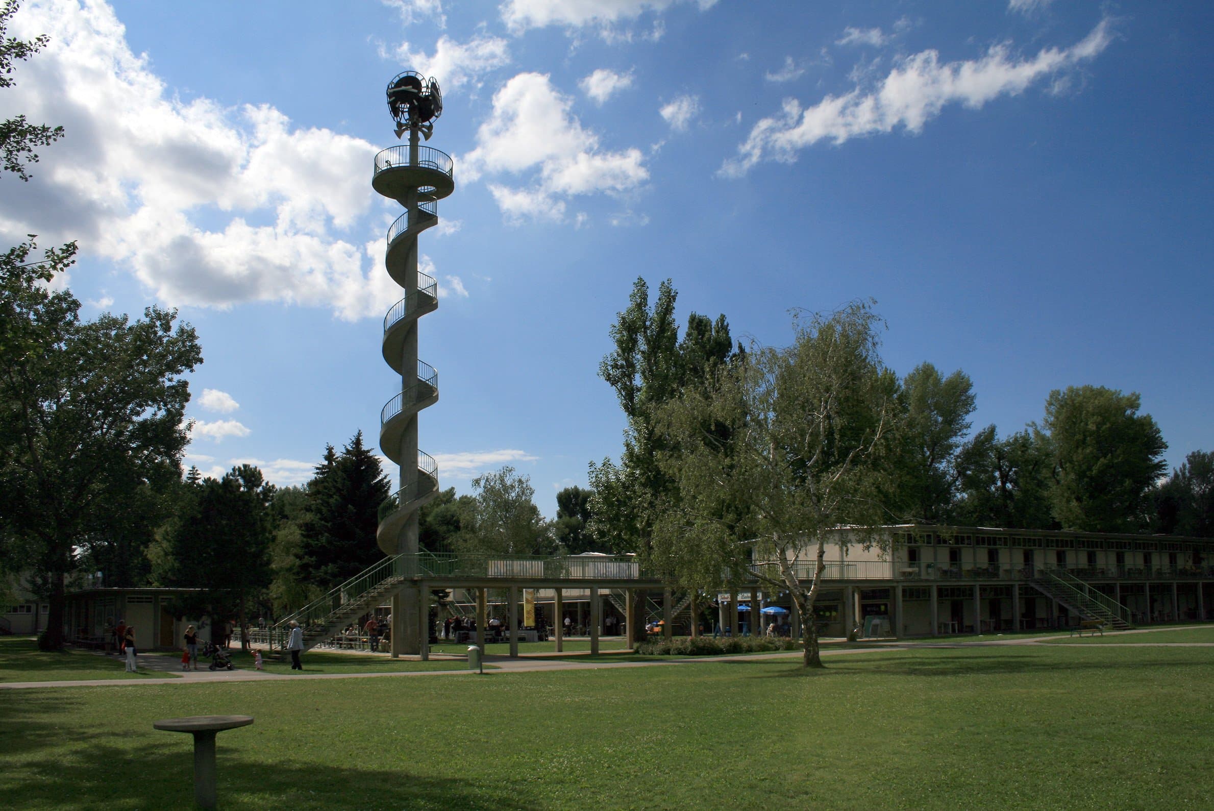Uhrturm des Gänsehäufels mit Wendeltreppe hinter einer baumbestandenen Liegewiese